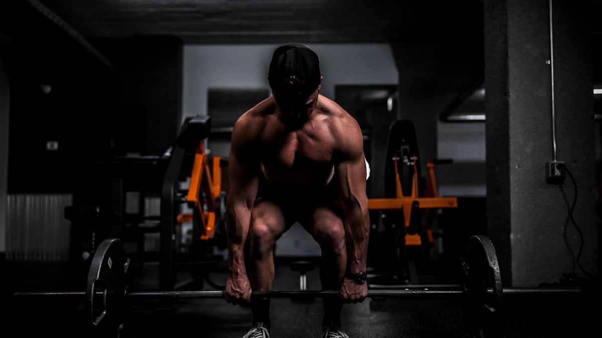Muscular person lifting barbell in gym